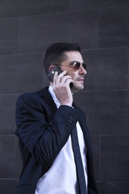 Erkek takım elbise ve cep telefonda konuşurken güneş gözlüğü