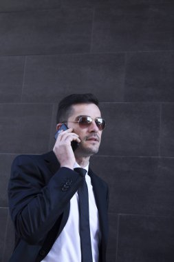 Erkek takım elbise ve cep telefonda konuşurken güneş gözlüğü
