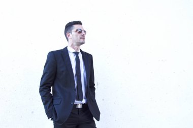 Takım elbise ve güneş gözlüğü adamla elleri ceplerinde portresi