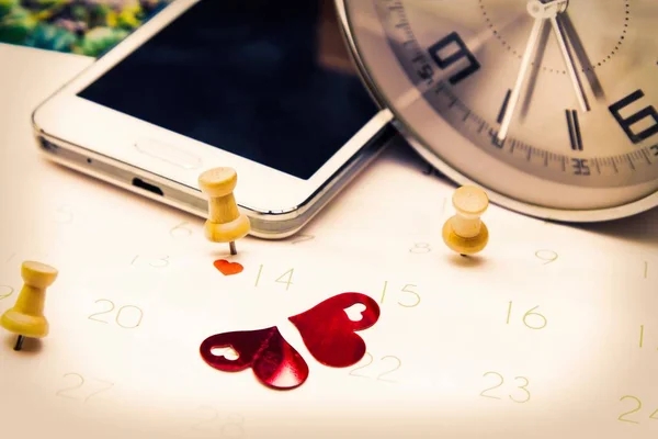 Valentine's concept. mobile phone and alarm clock with calendar