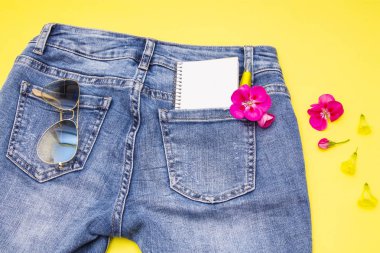 defter, kalem ve çiçek mavi kot pantolon cebinde