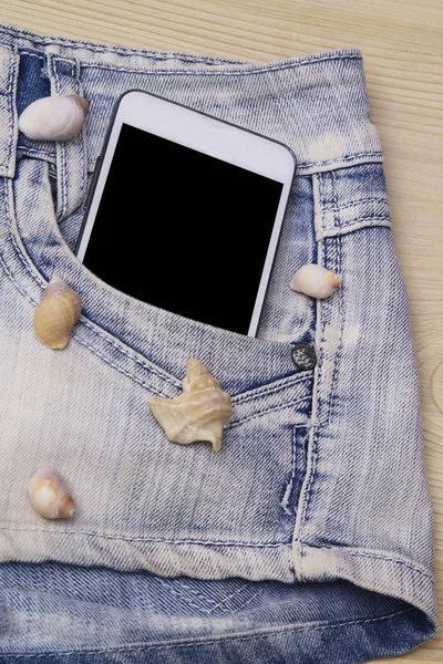 mobile phone and shells in the pocket blue jeans