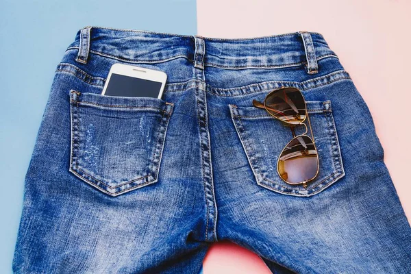 sunglasses and mobile phone in blue jeans pocket