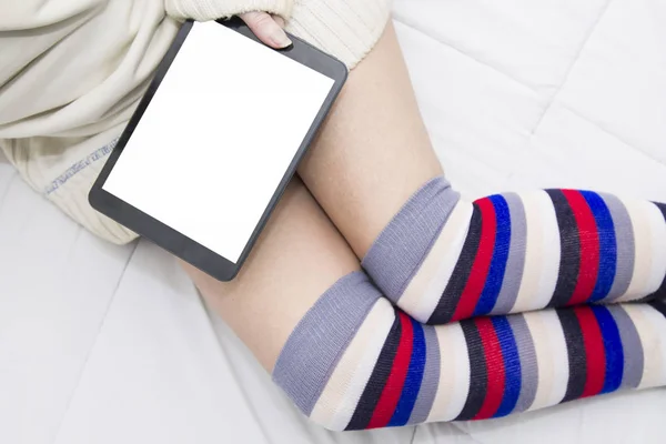 woman in long socks on top of the bed watching the tablet