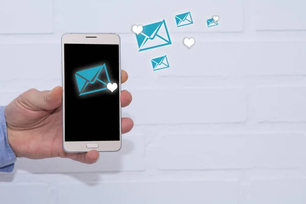 Love message for Valentine\'s Day: hearts in envelopes flying on a smartphone in the hands of man