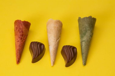 Sarı arka planda renkli dondurma külahları