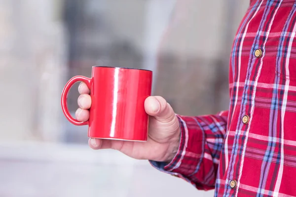 man in plaid shirt with cup in hand