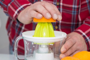 Adam meyve sıkacağı ile portakal suyu yapıyor.