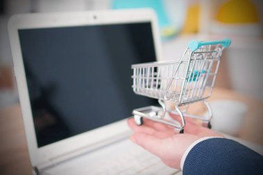 Ofisinde minyatür alışveriş arabası olan işadamı, alışveriş ve satış konsepti
