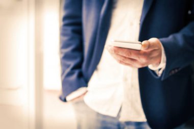 İş adamı ofisteki cep telefonunu kullanıyor.