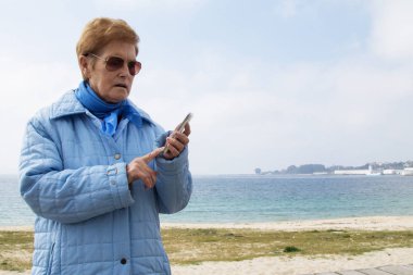 Dışarıda cep telefonunu kullanan son sınıf öğrencisi bir kadın.