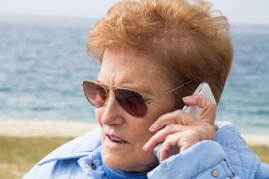 Dışarıda cep telefonunu kullanan son sınıf öğrencisi bir kadın.