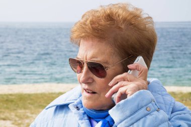 Dışarıda cep telefonunu kullanan son sınıf öğrencisi bir kadın.