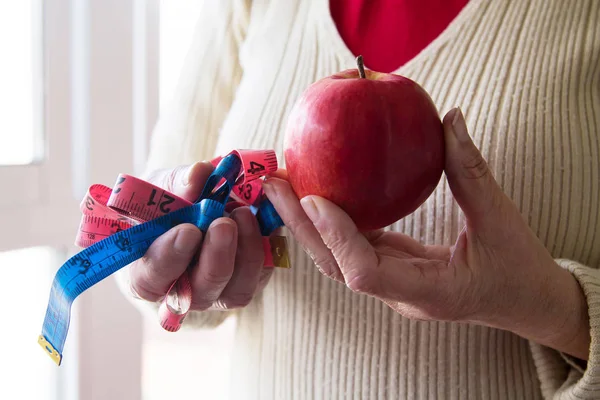 woman holding in hands apple and tape measure, concept of diet and health