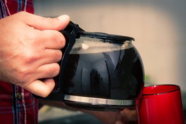 Adam mutfakta kahve içiyor.