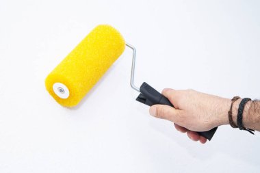Boya silindirli erkek el boyası duvar. Daire boyama, beyaz boyayla yenileme.