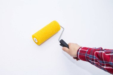 Boya silindirli erkek el boyası duvar. Daire boyama, beyaz boyayla yenileme.