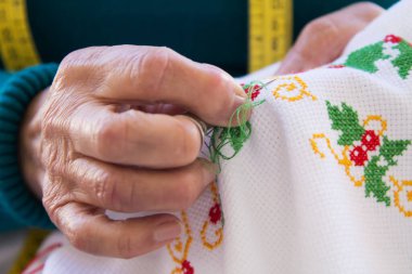 Kadın elleri masa örtüsü dikiyor.