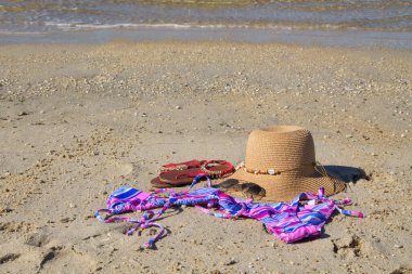 Sahilde yaz aksesuarları, şapka, güneş gözlükleri, bikini ve ayakkabı, tatil ve rahatlama konsepti