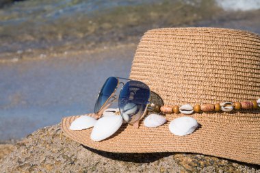 Plajda şapka ve güneş gözlüğü, yaz tatili ve dinlenme konsepti.