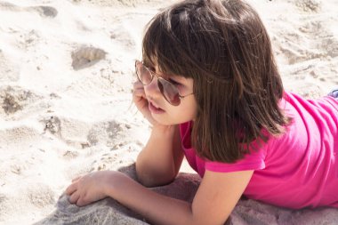 Kumsalda kumda uzanan bir kız yaz tatili ve dinlenme konsepti.