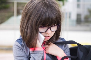 Okulun ya da kampüsün önünde cep telefonuyla üzgün ya da depresif bir öğrenci.