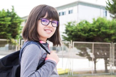 Okul kapısında sırt çantalı bir kız.