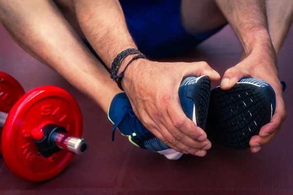 man doing gymnastic exercises on the floor with dumbbells