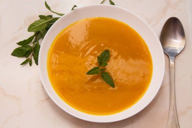 Arka planda balkabağı çorbası olan kase