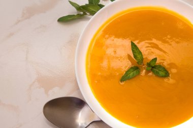 Arka planda balkabağı çorbası olan kase