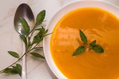 Arka planda balkabağı çorbası olan kase