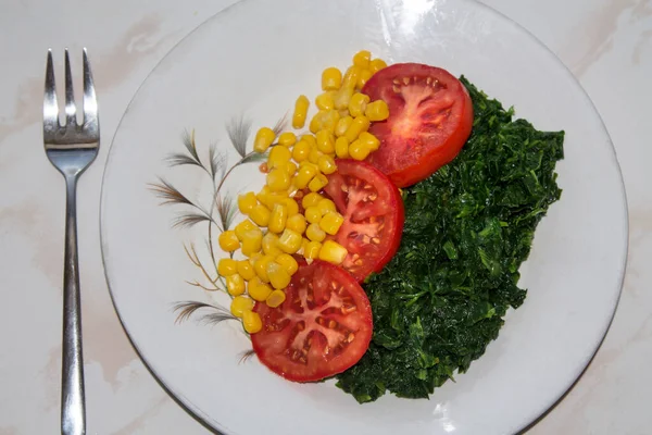 plate of tomato, corn and spinach salad close-up view, diet and health concept