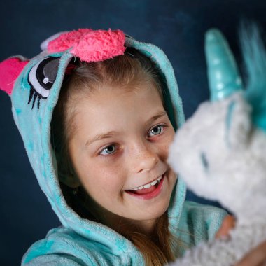 Kız pijamalı, tek boynuzlu atlar giyiyor.