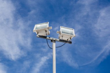 Spor stadyumu için sokak lambası direği, otopark, mavi gökyüzü ve bulutlu bir park. Boşluğu kopyala.