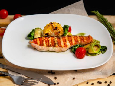 Beyaz tabakta sebzeli ızgara somon.