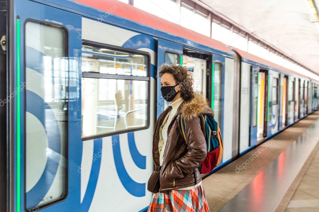 The women in a face mask is checking the phone message at the train 