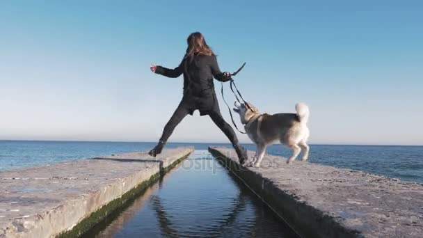 Kvinna leker med husky på seacoast — Stockvideo