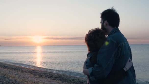 Pareja cariñosa en la playa durante la puesta del sol — Vídeos de Stock