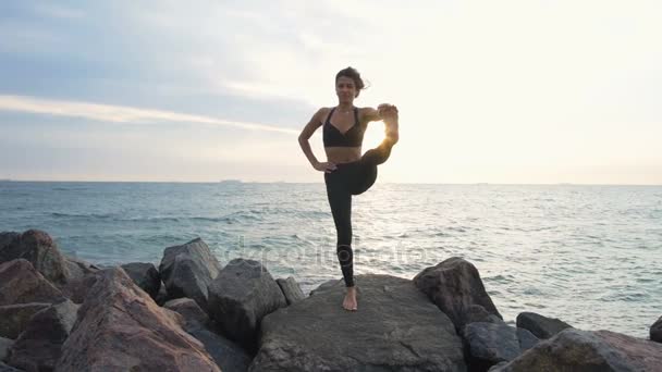 Жінка робить йогу на скелі — стокове відео