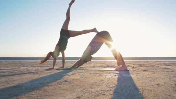 Pareja haciendo yoga en la playa — Vídeo de stock