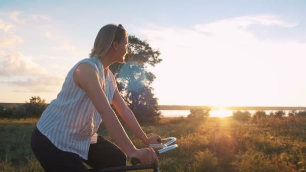 Hipster meisje paardrijden fiets bij zonsondergang — Stockvideo