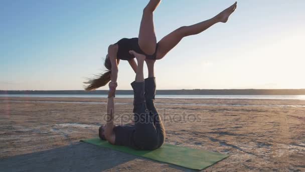 Pareja haciendo yoga durante la puesta del sol — Vídeo de stock