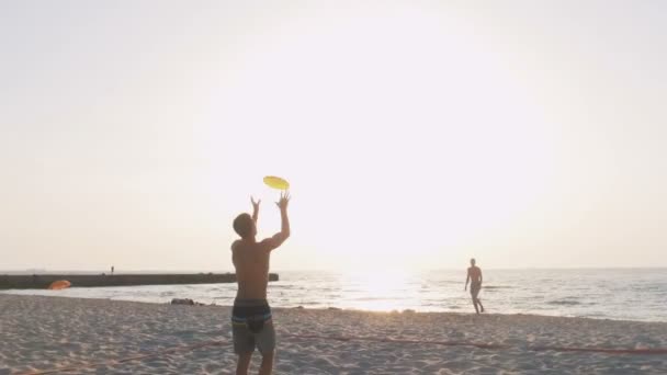 Mannen spelen frisbee op strand — Stockvideo