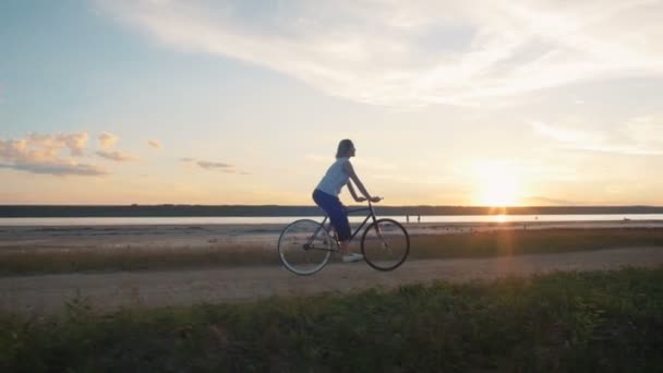 Hipster girl riding bike on seacoast — стоковое видео