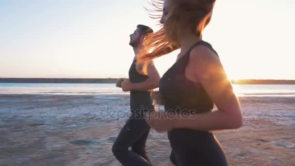 Deporte pareja corriendo en playa — Vídeo de stock