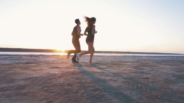 Спортивна пара біжить на пляжі — стокове відео