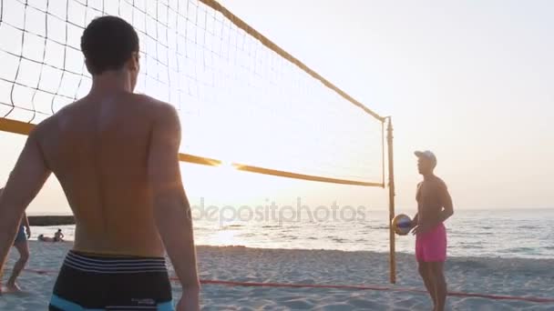 Mannen spelen volleybal bij zonsondergang — Stockvideo