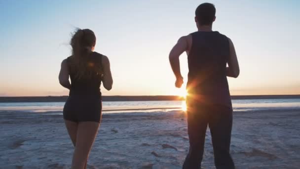 Спортивна пара біжить на пляжі — стокове відео