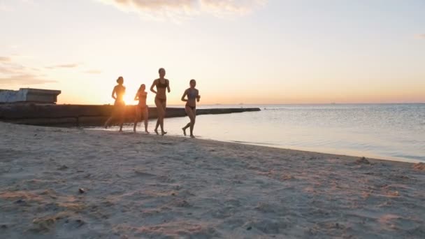 Mujeres corriendo en la playa al atardecer — Vídeo de stock