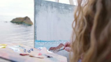 Sahilde deniz boyayan kadın.